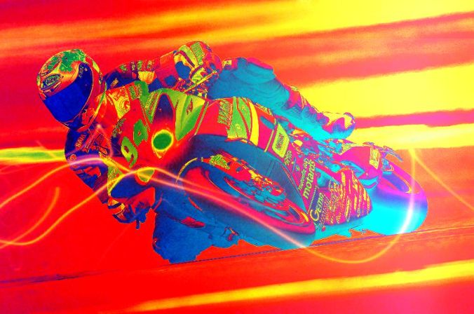 Picture of motorcycle racer on bike that is lying close to the track